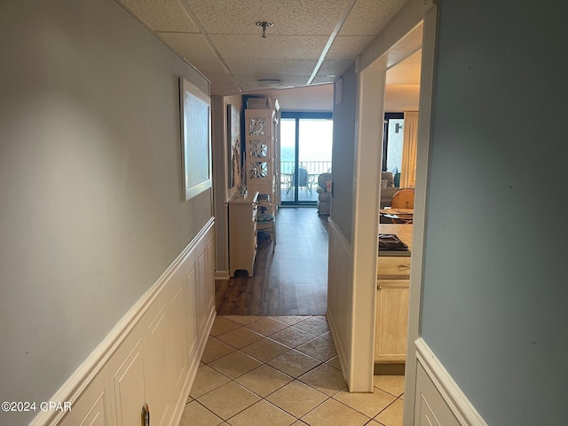 corridor featuring a drop ceiling and light tile patterned floors