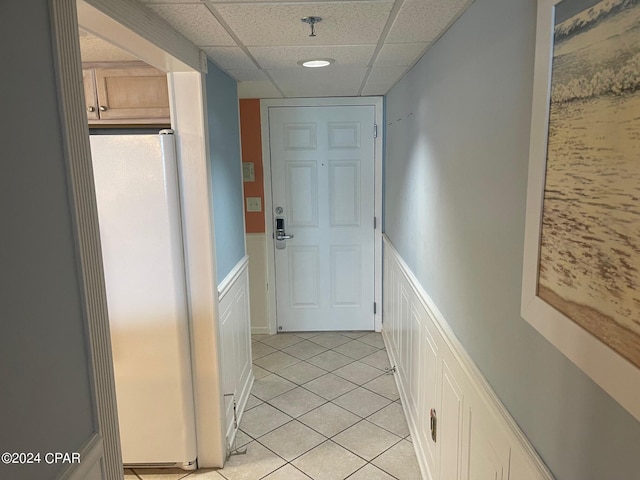 corridor featuring a paneled ceiling and light tile patterned floors