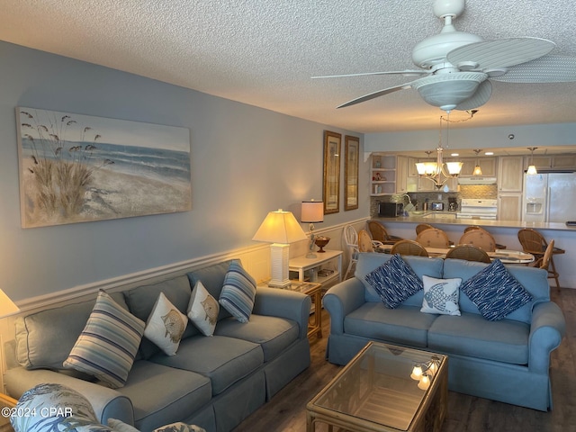 living room with a textured ceiling, dark hardwood / wood-style floors, and ceiling fan with notable chandelier