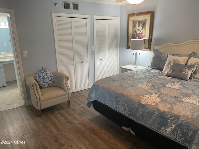 bedroom featuring ceiling fan, dark wood-type flooring, and two closets