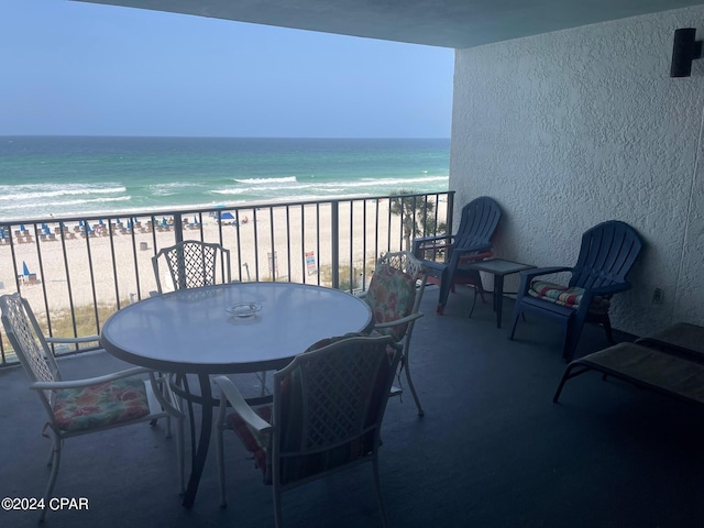 balcony with a water view and a view of the beach