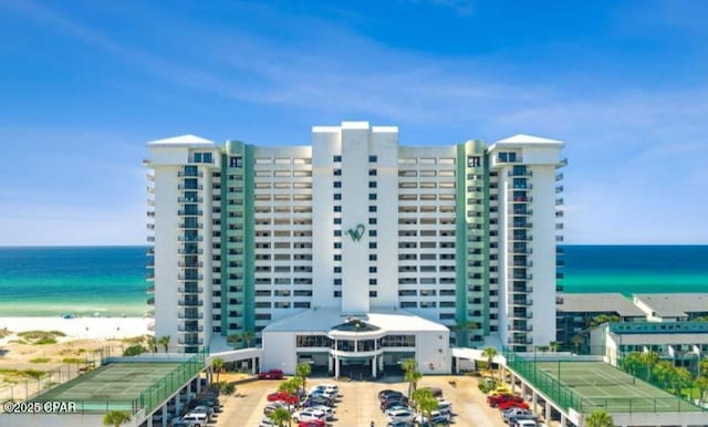 view of building exterior featuring a water view and a beach view