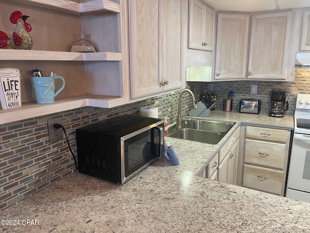 kitchen with light brown cabinets, backsplash, white range oven, and sink