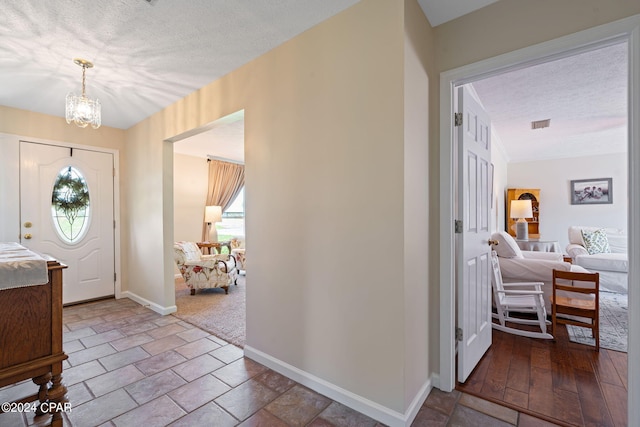 foyer entrance with plenty of natural light, a chandelier, and a textured ceiling