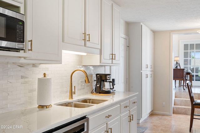 kitchen featuring white cabinetry, sink, tasteful backsplash, and a textured ceiling