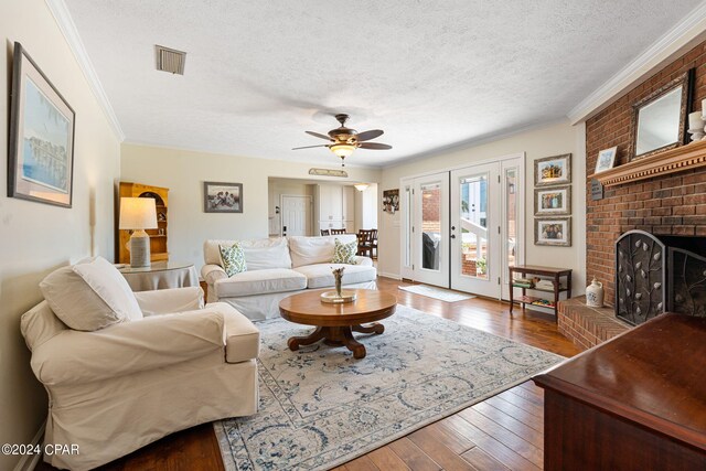 living room with a textured ceiling, a fireplace, ornamental molding, wood-type flooring, and ceiling fan