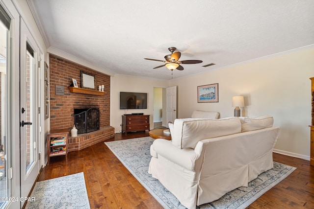 living room featuring a brick fireplace, hardwood / wood-style floors, ceiling fan, and crown molding