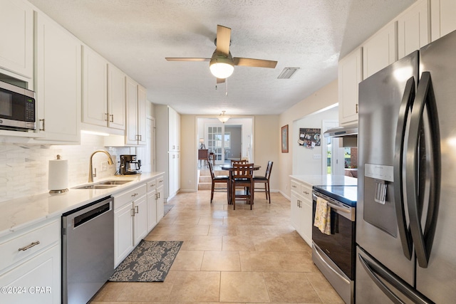 kitchen with sink, appliances with stainless steel finishes, a textured ceiling, white cabinets, and decorative backsplash