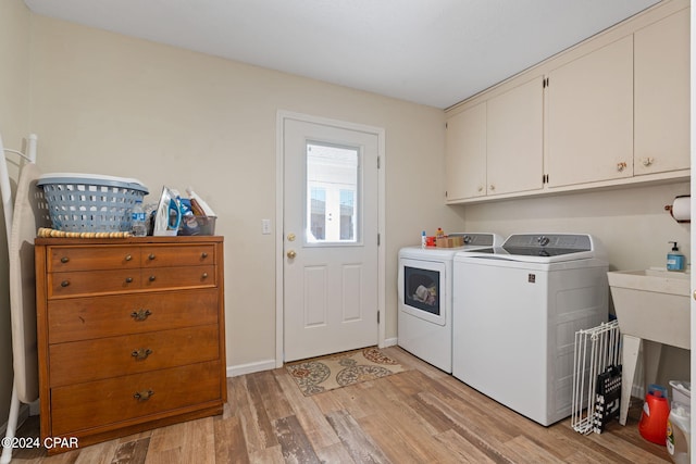 laundry room with washer and dryer, light hardwood / wood-style floors, and cabinets