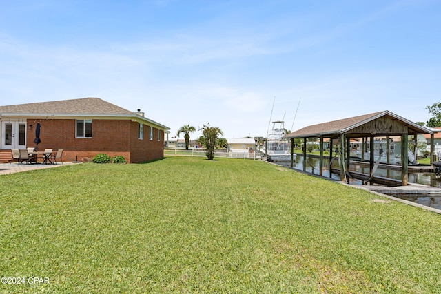 view of yard featuring a boat dock, a water view, and a patio area