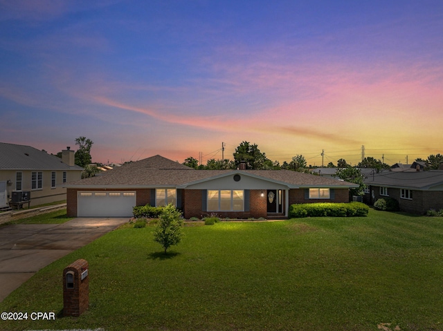 single story home with a yard, central AC unit, and a garage