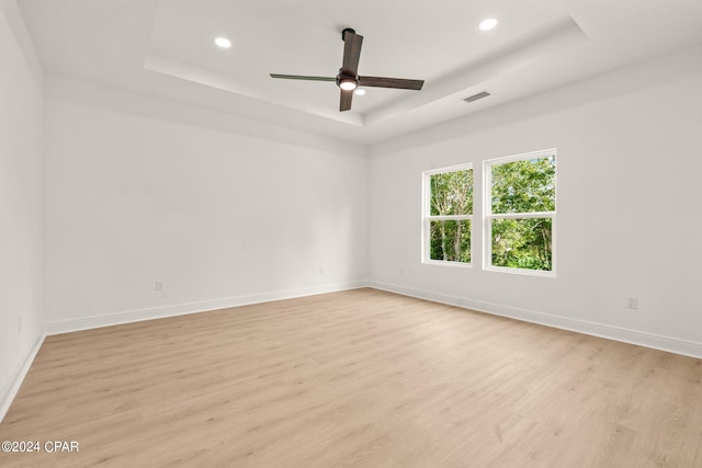 unfurnished room featuring ceiling fan, a tray ceiling, and light hardwood / wood-style floors