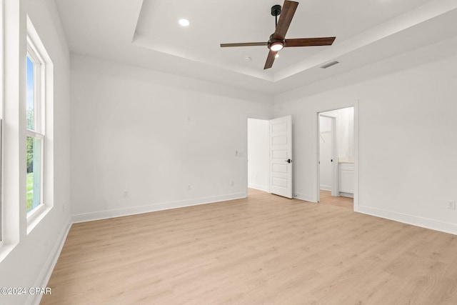 unfurnished bedroom featuring baseboards, a raised ceiling, and light wood-style floors