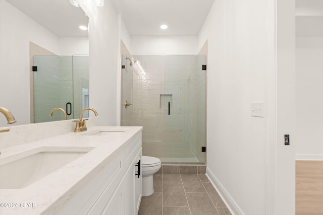bathroom featuring toilet, double vanity, a sink, and a shower stall