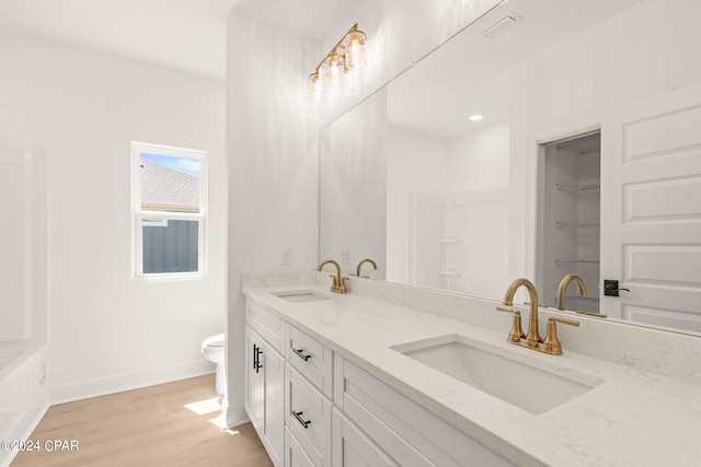 full bathroom featuring toilet, wood finished floors, a sink, and baseboards