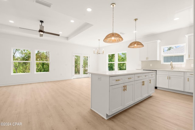 kitchen featuring hanging light fixtures, white cabinets, a center island, light hardwood / wood-style flooring, and ceiling fan