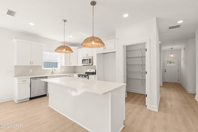 kitchen featuring white cabinets, pendant lighting, a kitchen island, appliances with stainless steel finishes, and light hardwood / wood-style floors