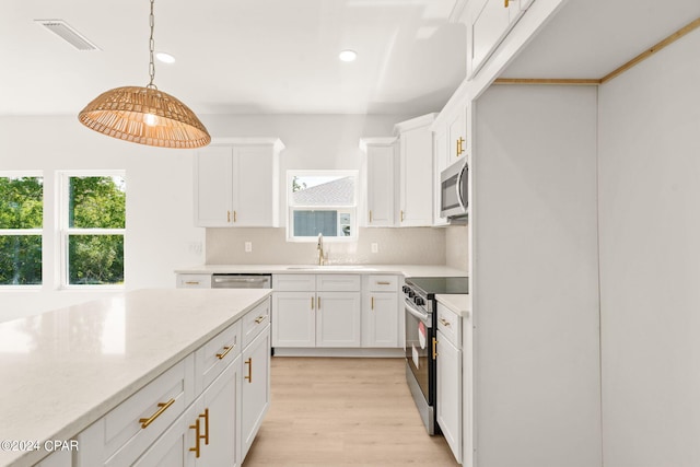 kitchen featuring white cabinets, pendant lighting, stainless steel appliances, light hardwood / wood-style flooring, and sink