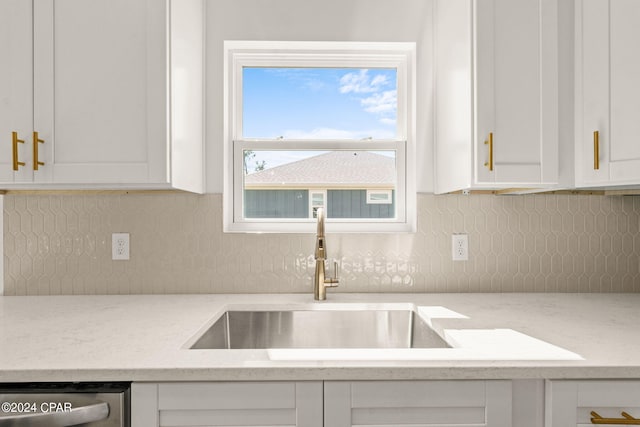 kitchen featuring decorative backsplash, a sink, dishwasher, and white cabinets