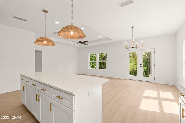 kitchen with ceiling fan with notable chandelier, white cabinets, light hardwood / wood-style flooring, and decorative light fixtures