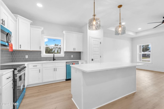 kitchen with white cabinets, appliances with stainless steel finishes, a center island, and light hardwood / wood-style floors