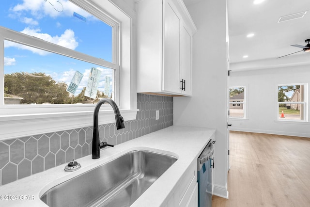 kitchen featuring decorative backsplash, white cabinetry, sink, and stainless steel dishwasher