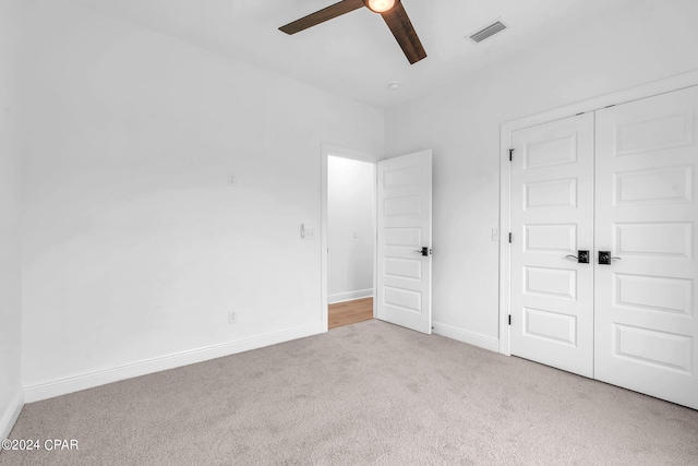 unfurnished bedroom with ceiling fan, light carpet, and a closet