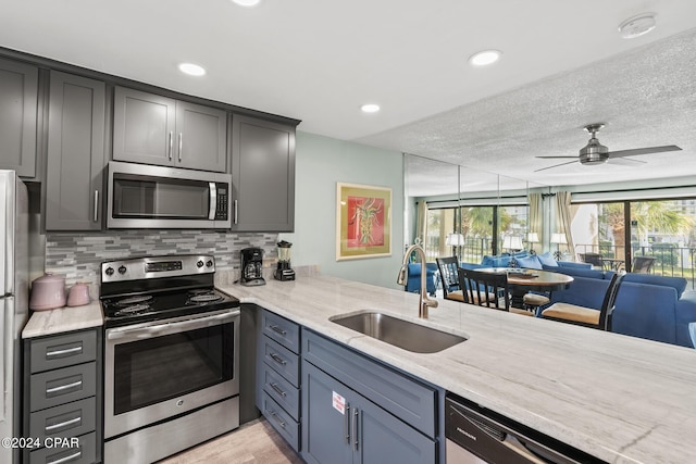 kitchen featuring sink, light hardwood / wood-style flooring, ceiling fan, appliances with stainless steel finishes, and kitchen peninsula