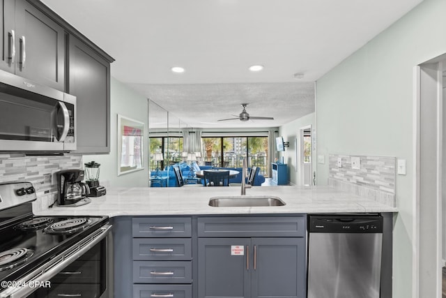 kitchen with backsplash, kitchen peninsula, light stone counters, and stainless steel appliances