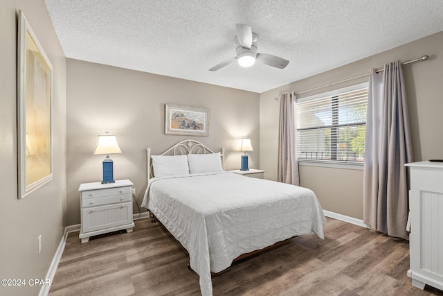 bedroom with a textured ceiling, hardwood / wood-style flooring, and ceiling fan