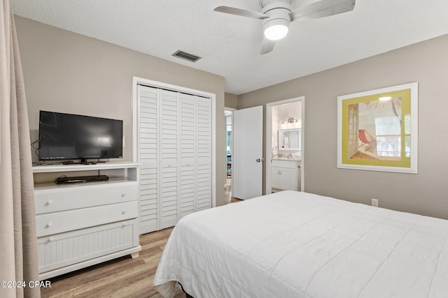 bedroom with connected bathroom, ceiling fan, a textured ceiling, a closet, and light wood-type flooring