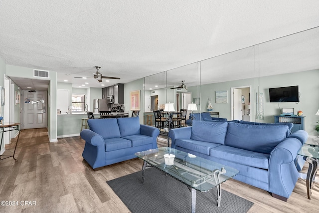 living room with ceiling fan, hardwood / wood-style floors, and a textured ceiling