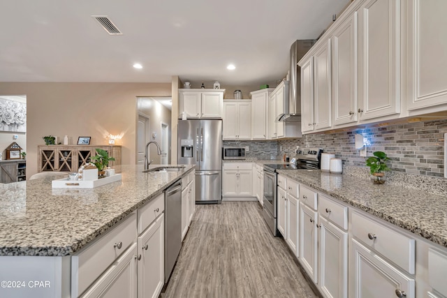 kitchen featuring light hardwood / wood-style floors, white cabinetry, appliances with stainless steel finishes, light stone counters, and backsplash