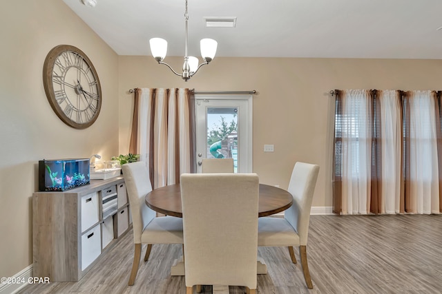 dining space with a notable chandelier and light hardwood / wood-style floors