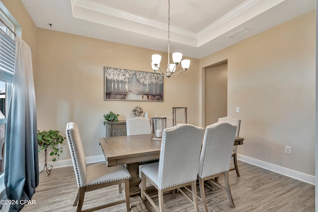 dining space featuring a healthy amount of sunlight, an inviting chandelier, hardwood / wood-style floors, and a raised ceiling