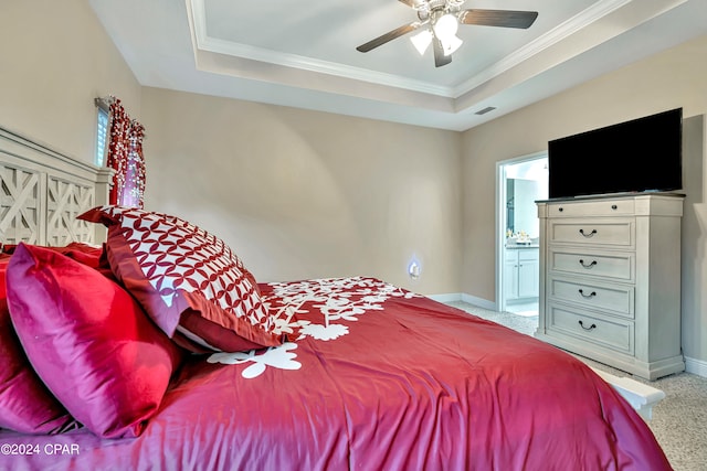 bedroom with crown molding, connected bathroom, ceiling fan, and a raised ceiling