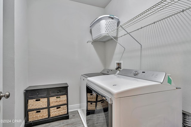 clothes washing area with separate washer and dryer, hookup for a washing machine, and light wood-type flooring