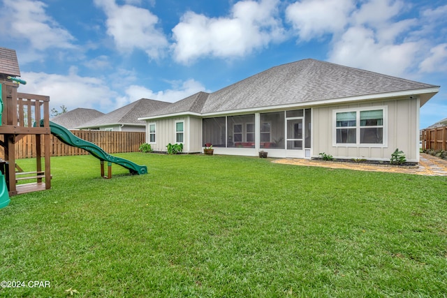 back of house with a playground, a sunroom, and a yard