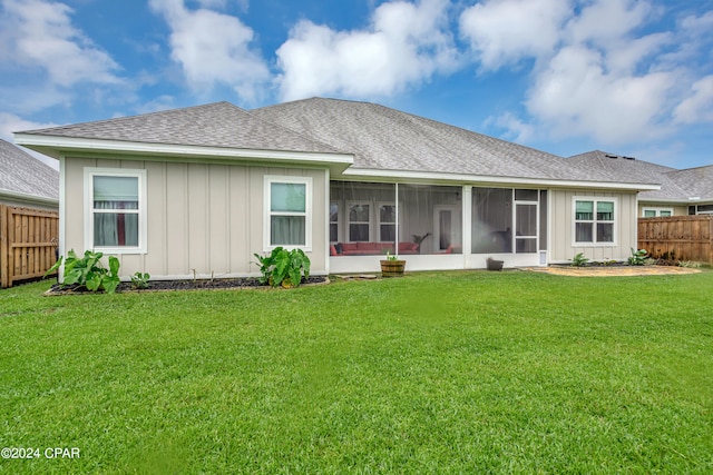 rear view of house with a sunroom and a lawn