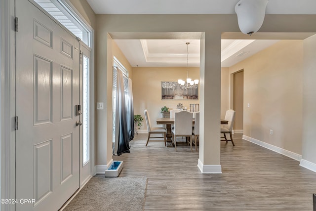 entryway with a notable chandelier, hardwood / wood-style flooring, plenty of natural light, and a raised ceiling