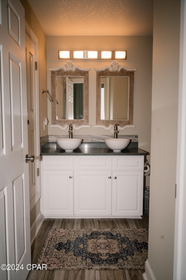 bathroom featuring a textured ceiling, hardwood / wood-style flooring, and double sink vanity