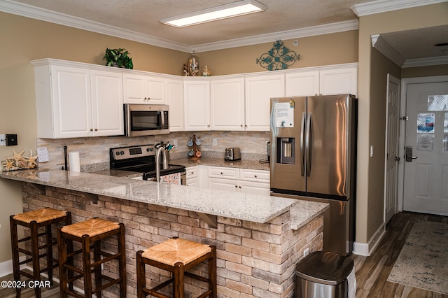 kitchen featuring light stone counters, dark hardwood / wood-style flooring, kitchen peninsula, stainless steel appliances, and a breakfast bar