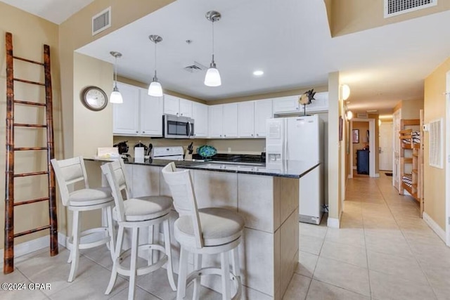 kitchen featuring white cabinetry, white refrigerator with ice dispenser, kitchen peninsula, pendant lighting, and a kitchen bar