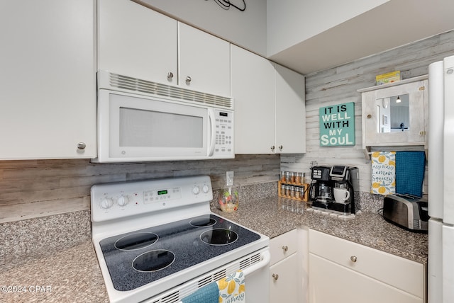 kitchen with white appliances, white cabinets, and wood walls