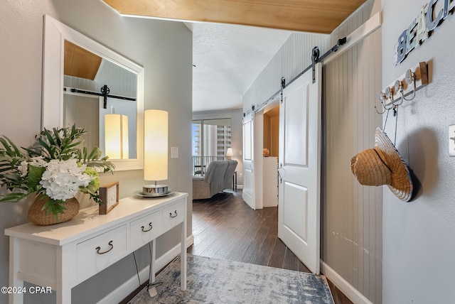 interior space with a barn door, a textured ceiling, and dark hardwood / wood-style floors