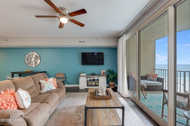 living room featuring ceiling fan, a water view, and wood-type flooring