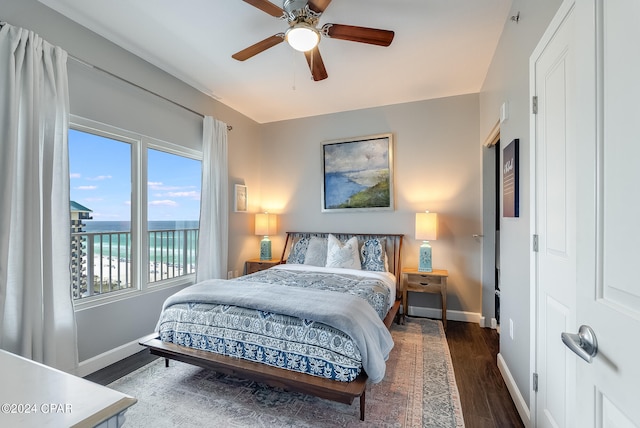 bedroom featuring ceiling fan, dark hardwood / wood-style flooring, and a water view