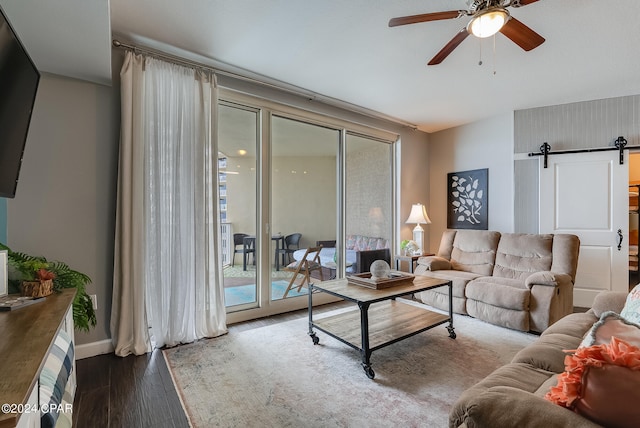 living room with hardwood / wood-style floors, a barn door, and ceiling fan