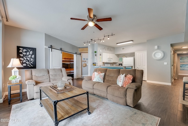 living room with a barn door, track lighting, ceiling fan, and hardwood / wood-style floors