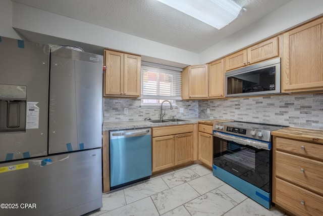 kitchen featuring decorative backsplash, appliances with stainless steel finishes, light brown cabinetry, a textured ceiling, and sink